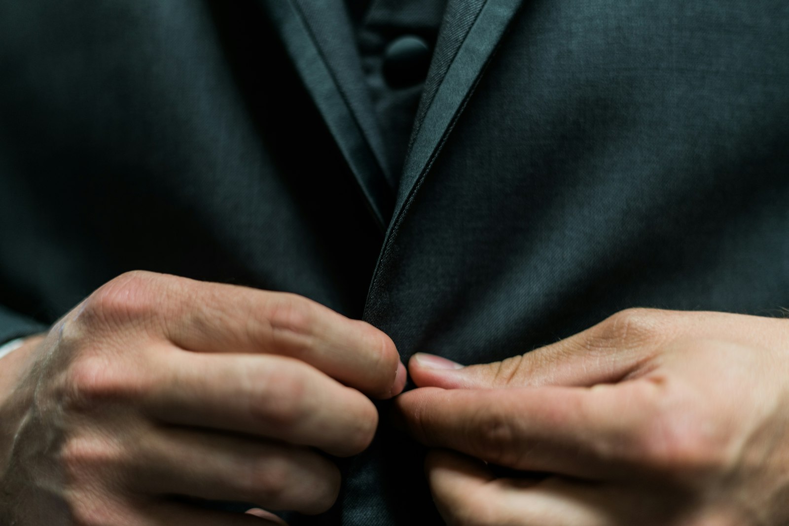 Hands buttoning a dark suit jacket
