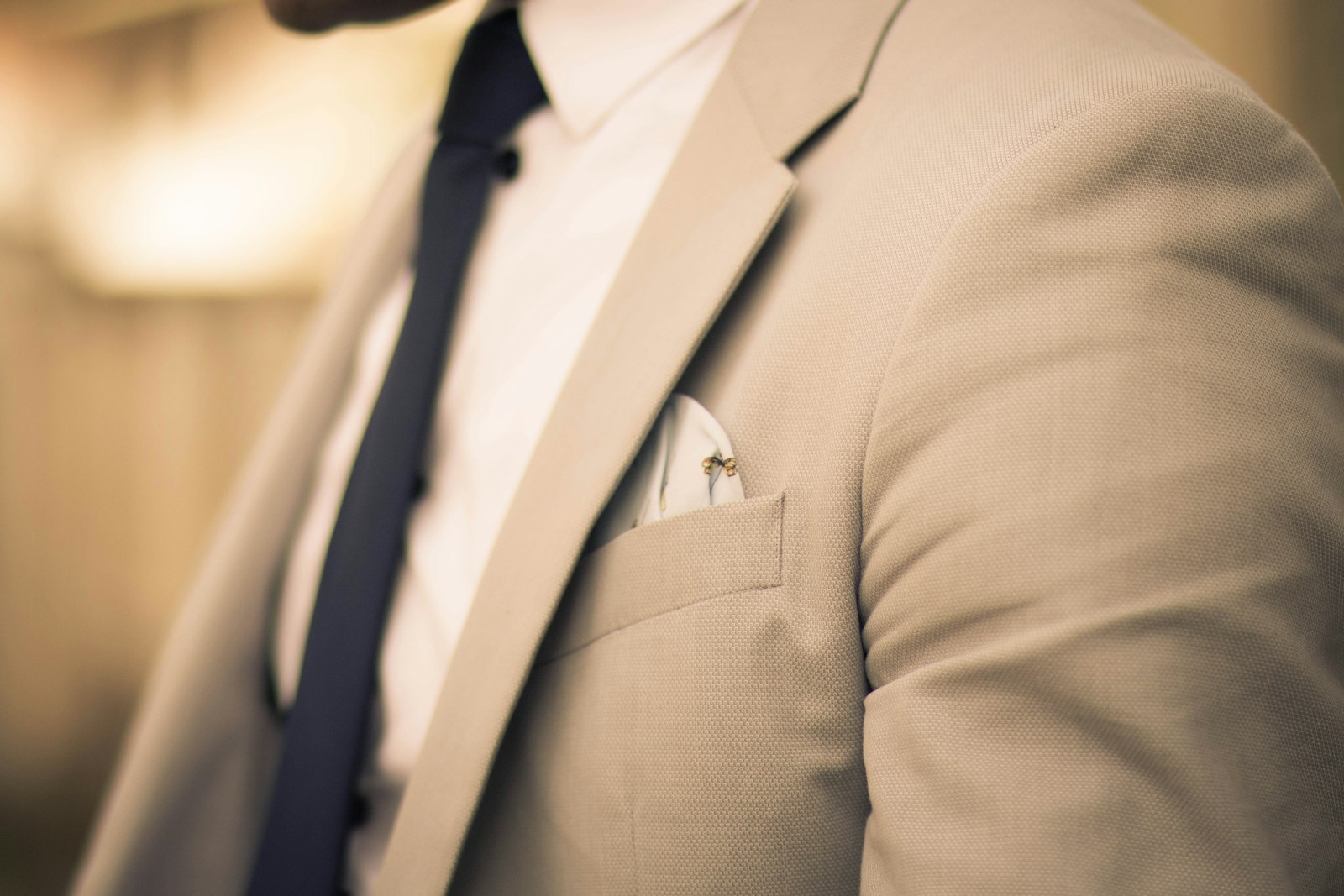 Man in a beige suit jacket and navy tie