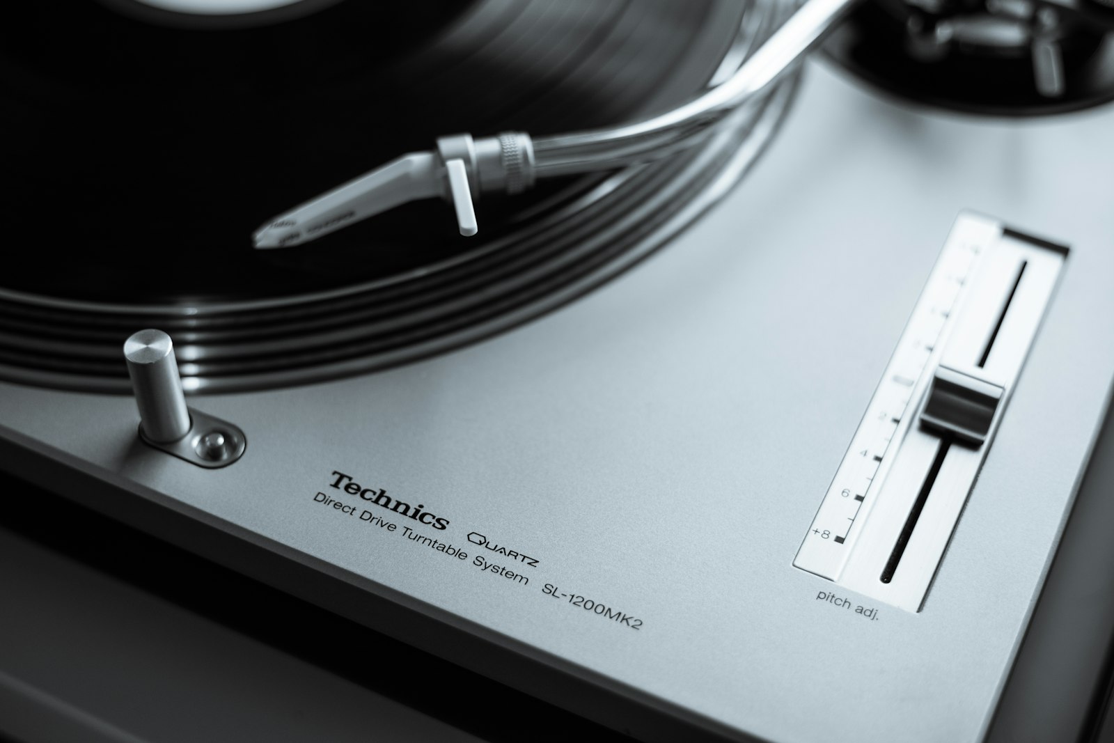 Close-up of a turntable tonearm and pitch fader