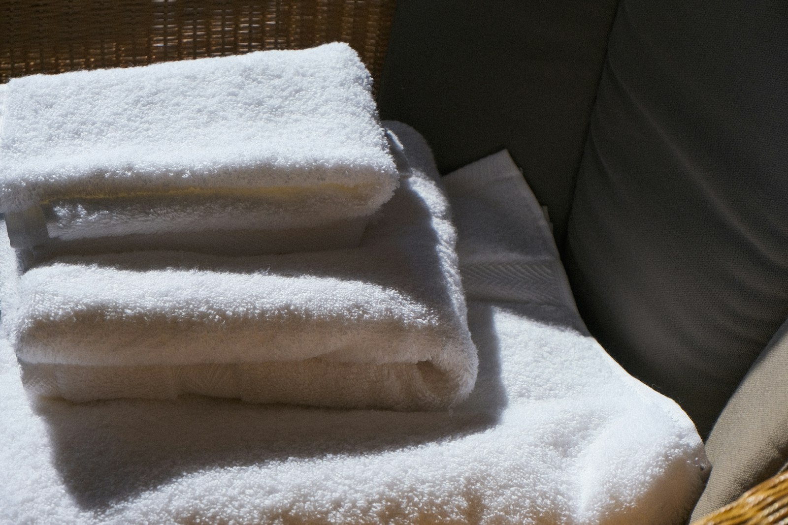A stack of fresh white towels folded on a chair.