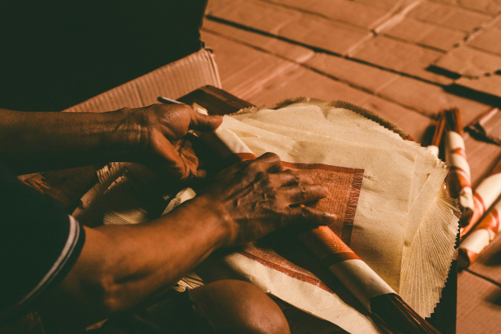 Hands handling sheets of printed paper in warm light