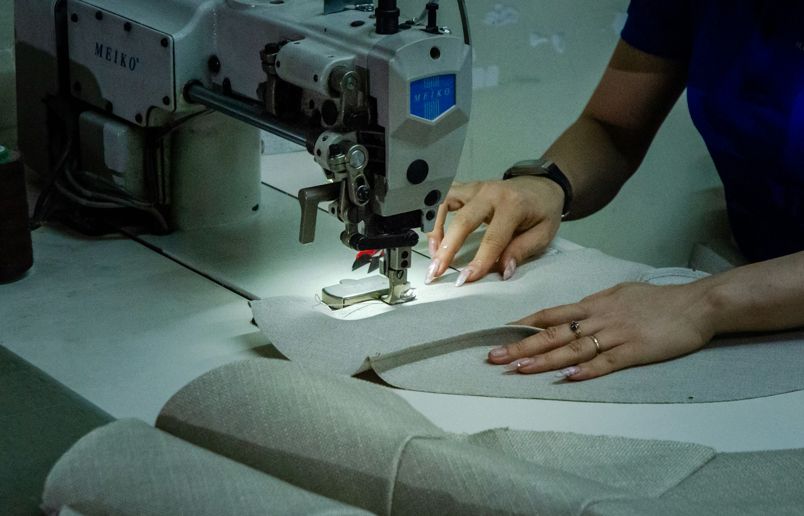 Tailor guiding fabric through a sewing machine