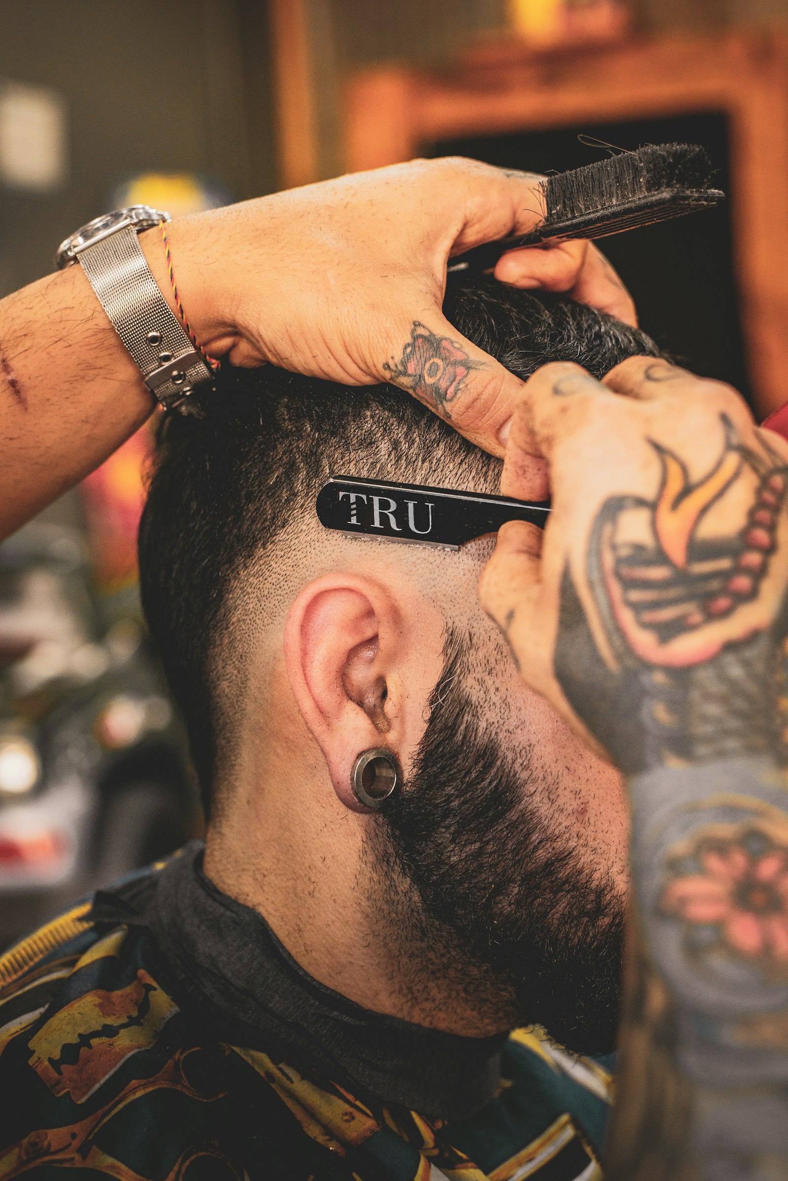 Barber trimming a bearded man's hair with a comb and clippers