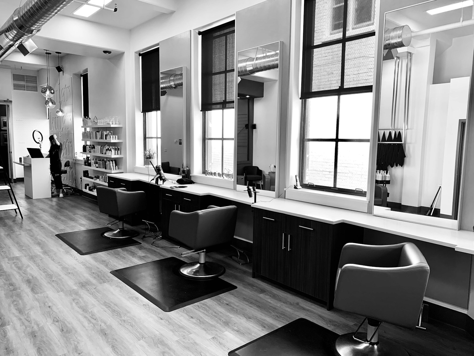 Black and white hair salon with chairs by tall windows