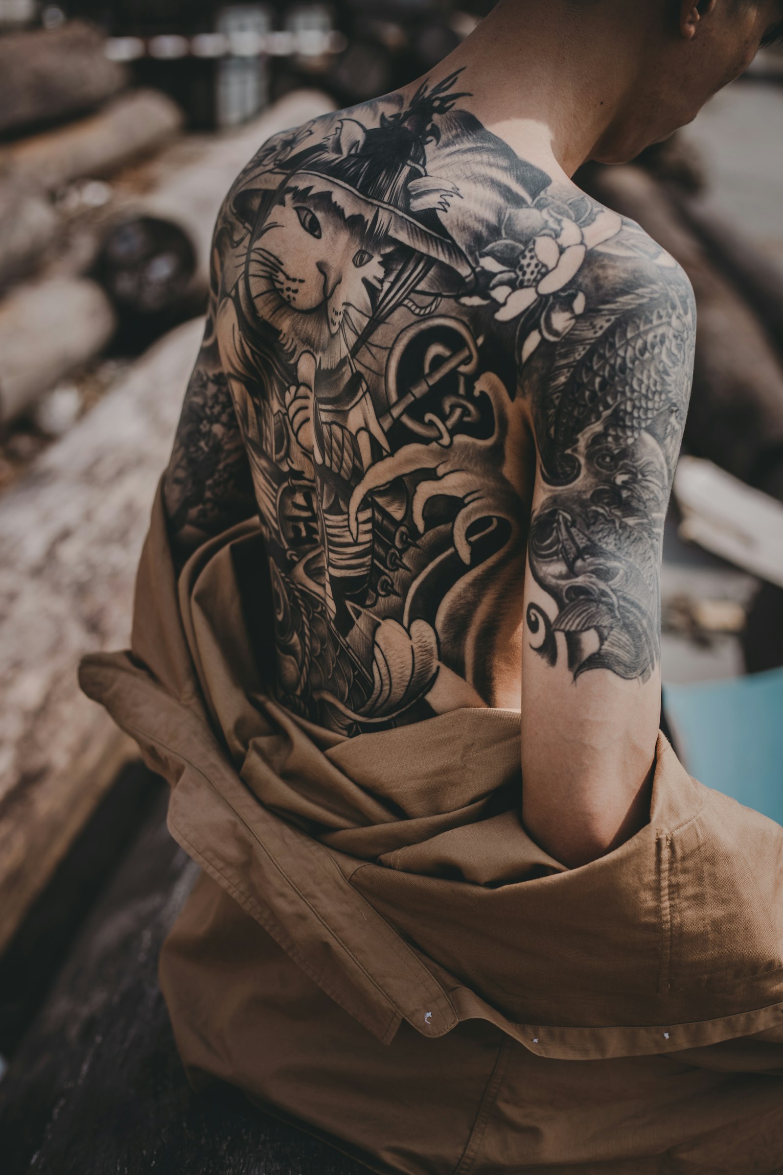 Large black and grey tattoo covering a person's shoulder, arm and back
